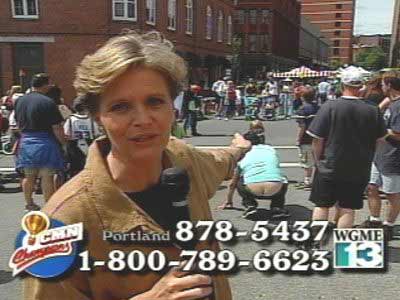 TV news image of an anchorwoman pointing out something while a man squats in the background and shows a refrigerator repairman butt crack.